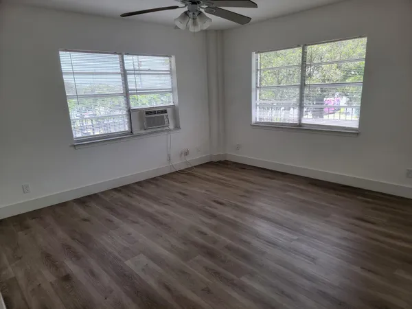 a view of an empty room with wooden floor and a window