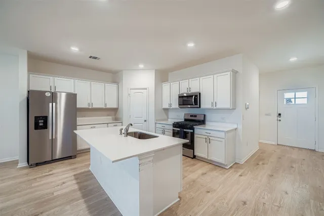 a kitchen with a refrigerator a stove top oven a sink and cabinets