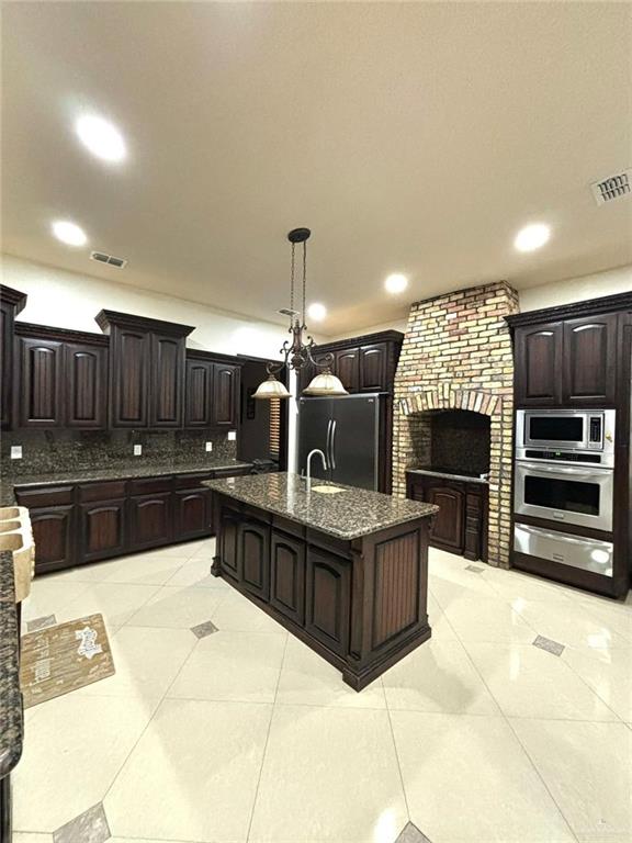 336 Navarro Street Pharr, TX 78577 - Photo 11 of 32 Kitchen featuring appliances with stainless steel finishes, backsplash, light tile patterned flooring, dark brown cabinets, and recessed lighting