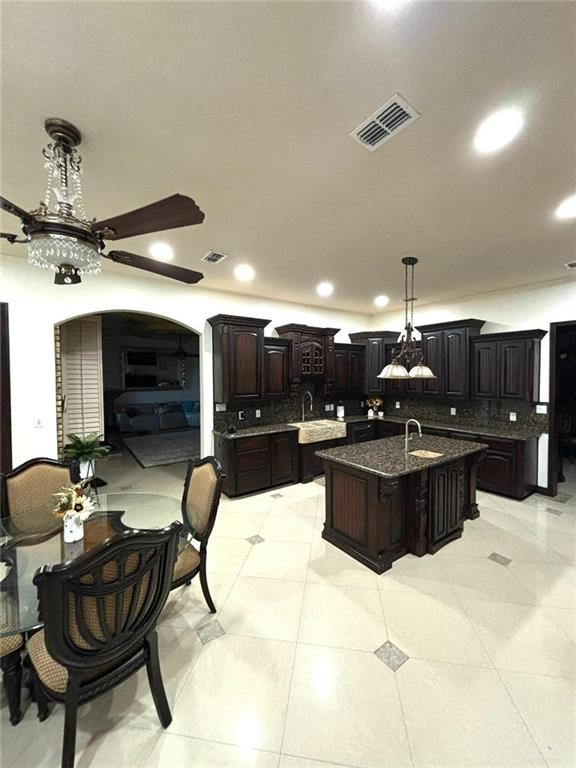 336 Navarro Street Pharr, TX 78577 - Photo 13 of 32 Kitchen with decorative backsplash, a kitchen island with sink, arched walkways, a ceiling fan, and recessed lighting