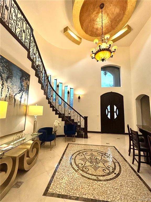 336 Navarro Street Pharr, TX 78577 - Photo 4 of 32 Entryway with a high ceiling, inlaid floor details, a chandelier, a tray ceiling, and stairway