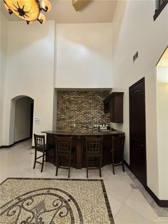 336 Navarro Street Pharr, TX 78577 - Photo 7 of 32 Kitchen with a high ceiling, arched walkways, dark brown cabinets, light tile patterned floors, and inlaid floor details