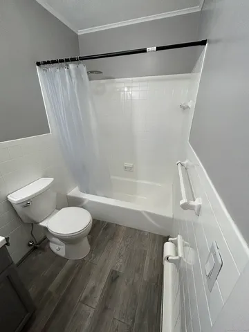a view of an empty room with wooden floor and window