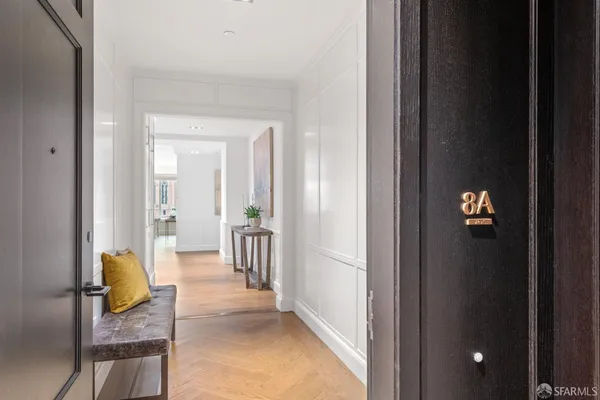 a view of a hallway with wooden floor and a living room