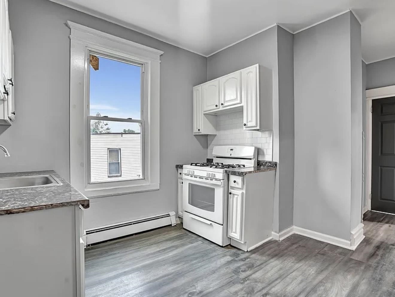 49 Tichenor Terrace, Unit 2 Irvington, NJ 07111 - Photo 1 of 9 a kitchen with granite countertop white cabinets and white appliances