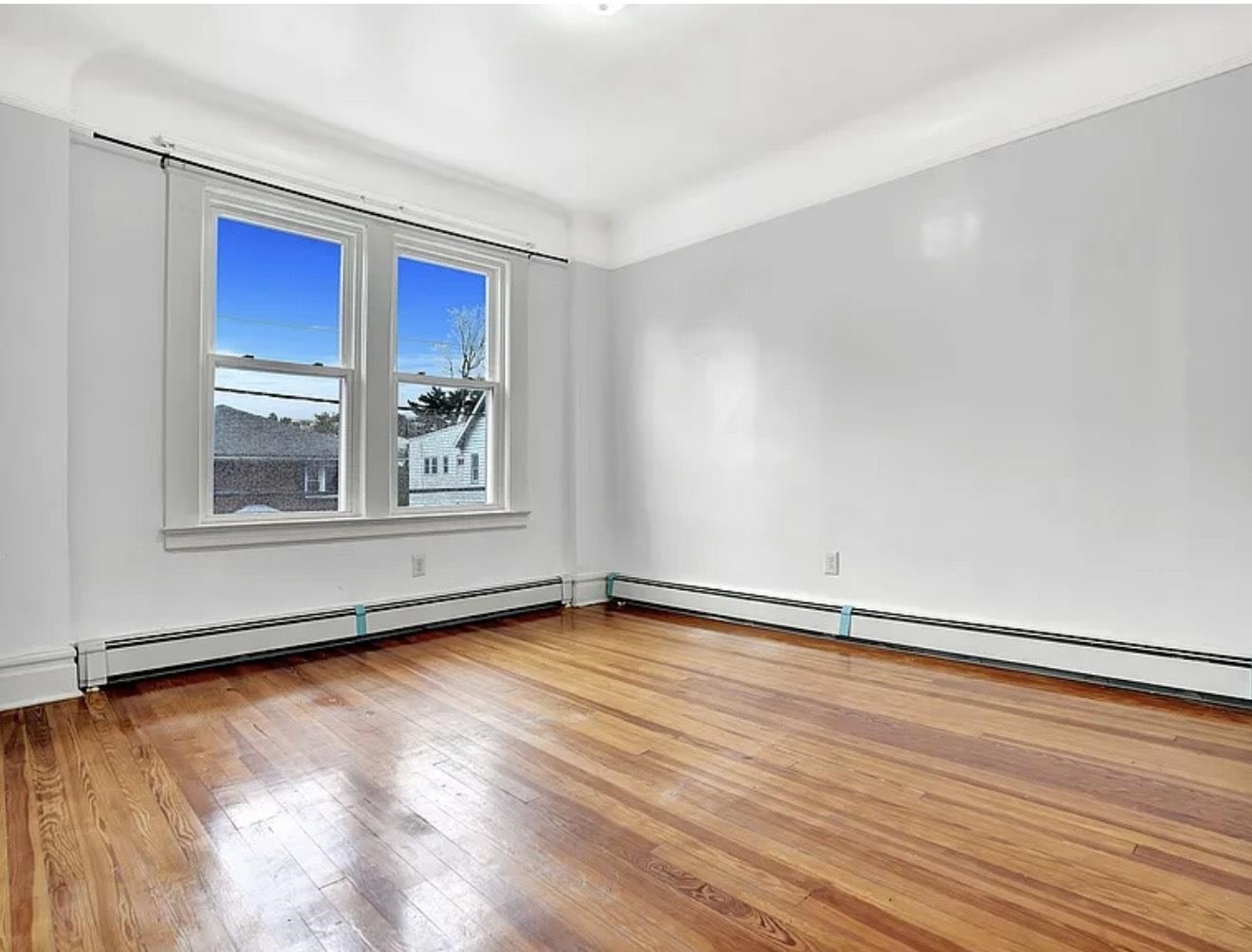 49 Tichenor Terrace, Unit 2 Irvington, NJ 07111 - Photo 3 of 9 a view of an empty room with a window and wooden floor