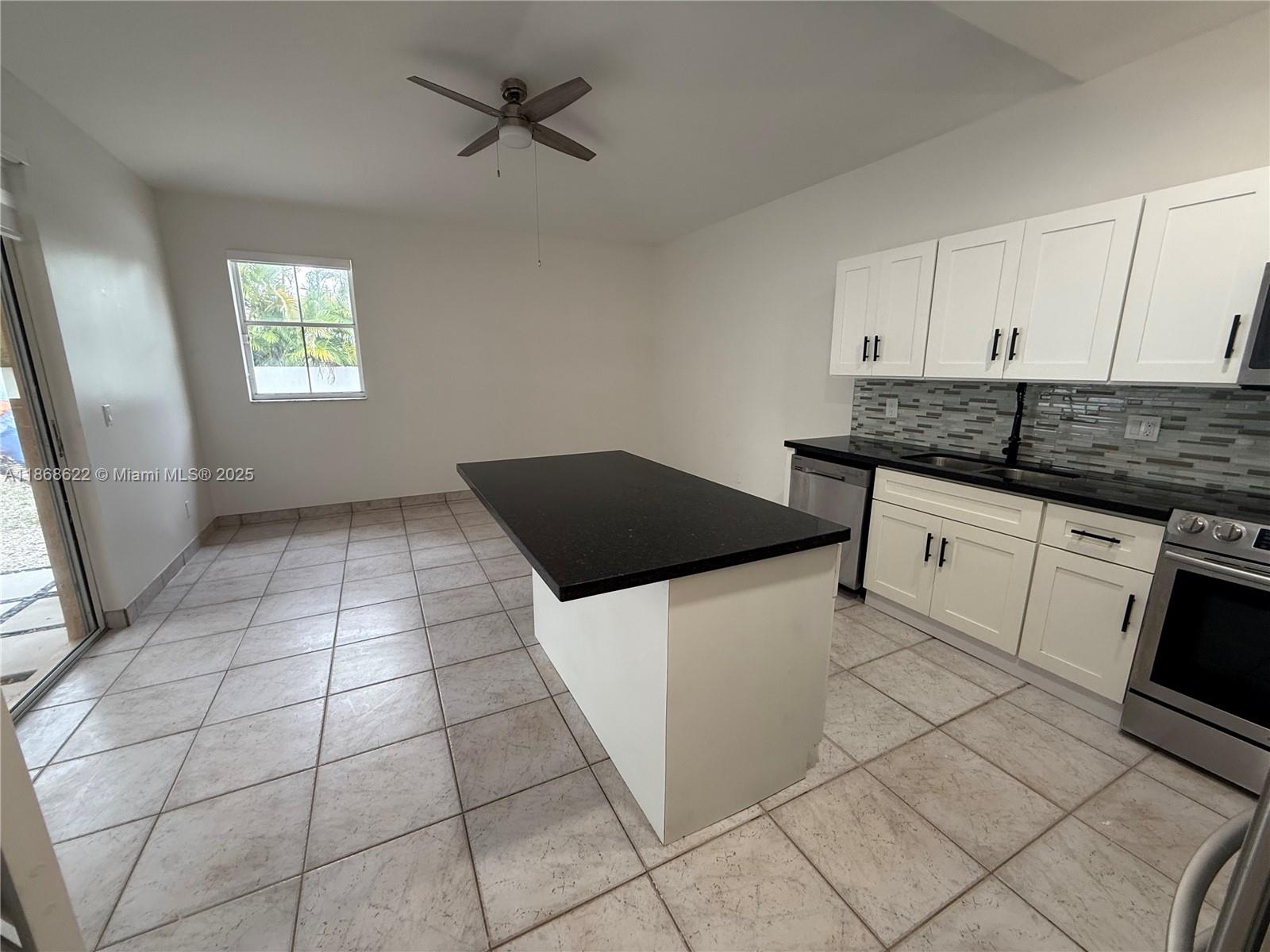 6955 Southwest 148 Lane Davie, FL 33331 - Photo 11 of 22 a kitchen with granite countertop a stove a sink and a microwave
