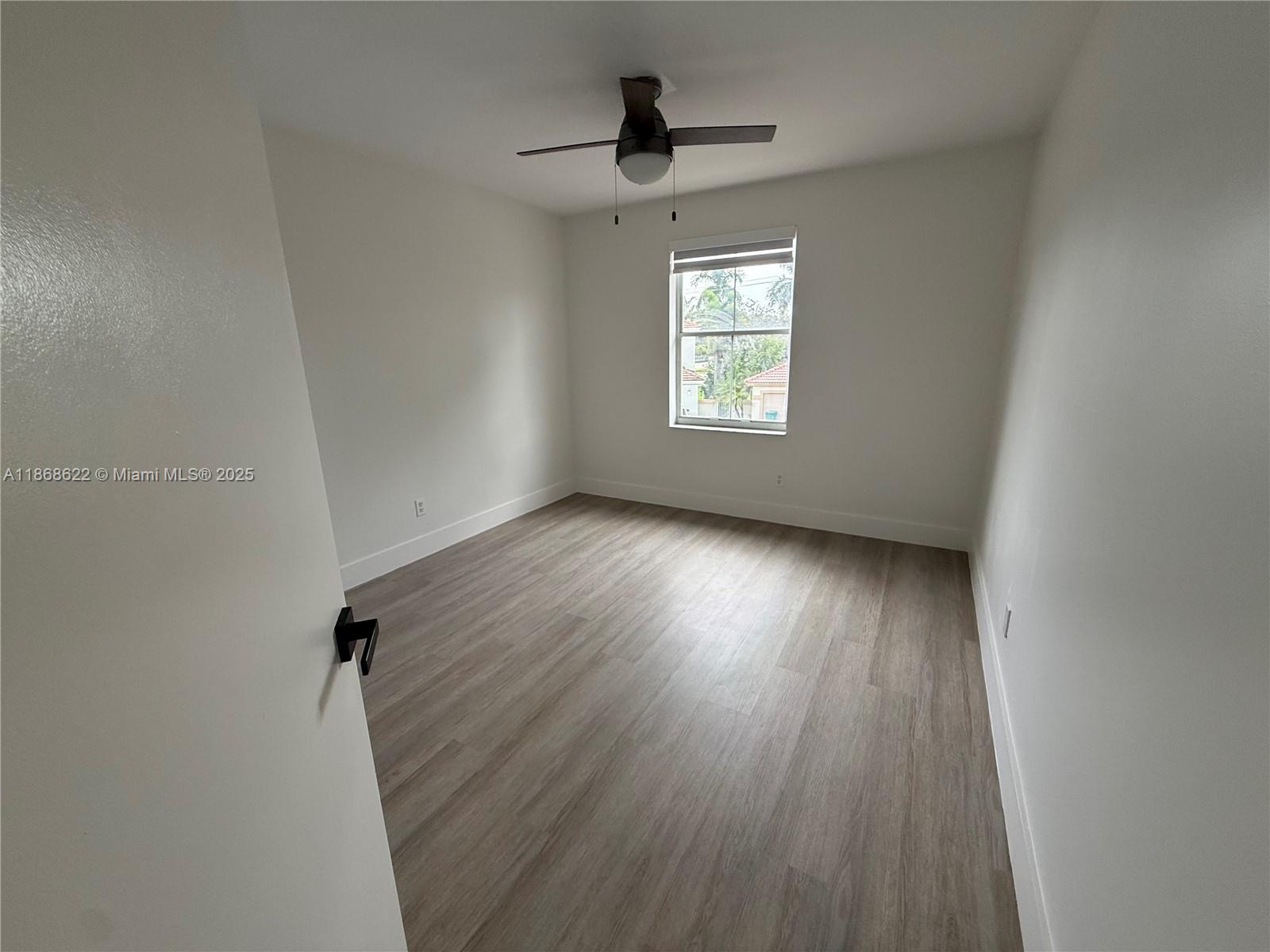 6955 Southwest 148 Lane Davie, FL 33331 - Photo 18 of 22 an empty room with wooden floor chandelier fan and windows