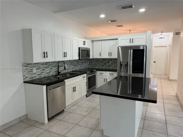 a kitchen with stainless steel appliances granite countertop a stove a sink and a refrigerator