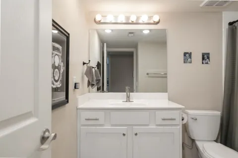a bathroom with a sink vanity granite toilet and a mirror