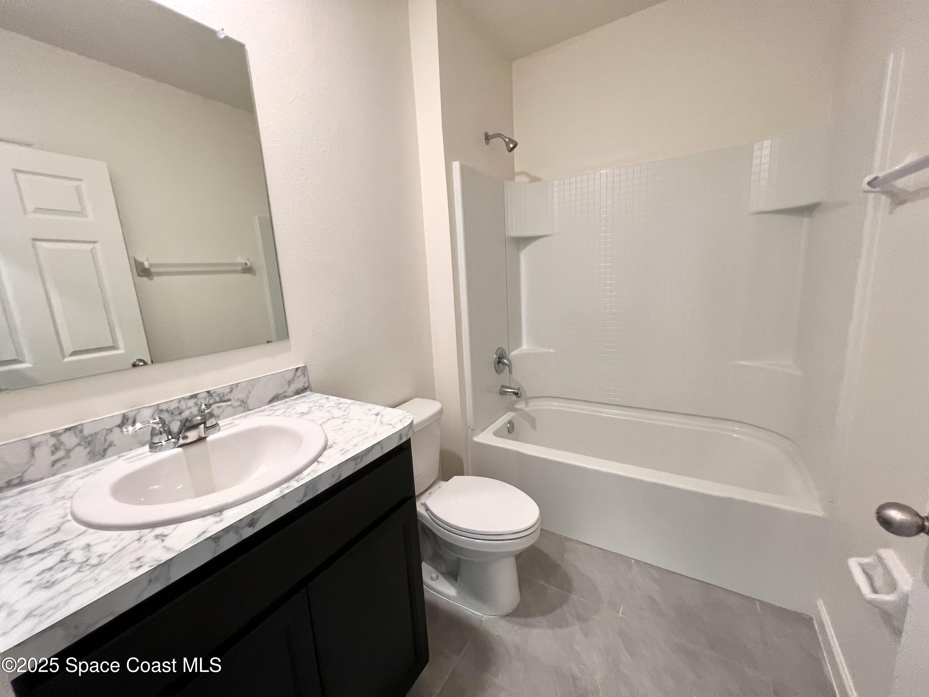 4631 Talbot Boulevard Cocoa, FL 32926 - Photo 6 of 24 a bathroom with a granite countertop sink a toilet a mirror a bathtub and shower