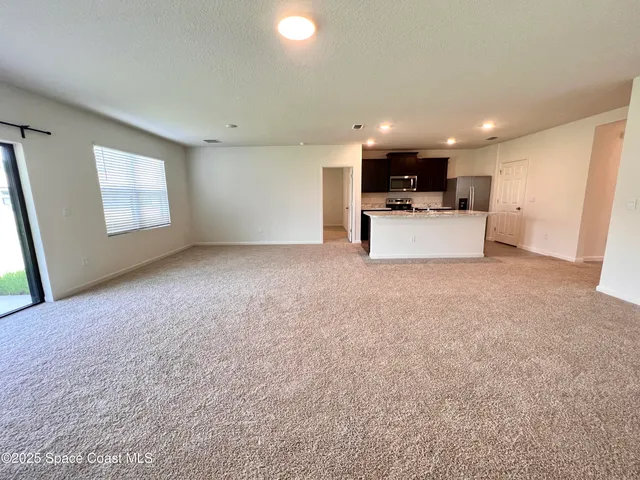 a large kitchen with stainless steel appliances kitchen island granite countertop a refrigerator a sink a stove and black cabinets