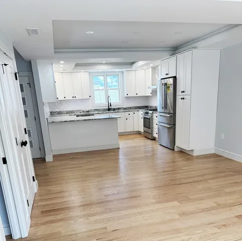 a kitchen with stainless steel appliances a refrigerator and wooden floor