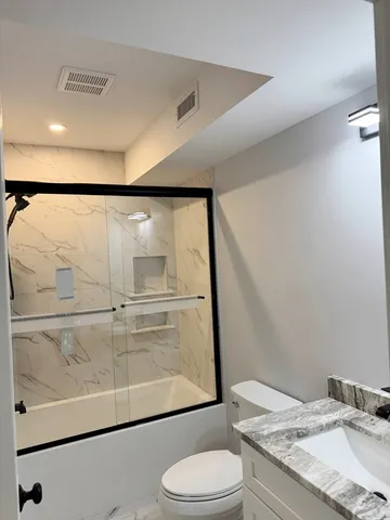 a bathroom with a granite countertop sink mirror vanity and toilet