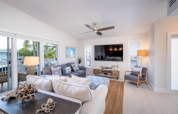 a kitchen with stainless steel appliances granite countertop a stove a sink a living room with living room furniture and a flat screen tv