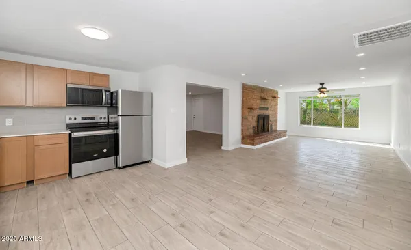 a view of a livingroom with a fireplace a ceiling fan and wooden floor