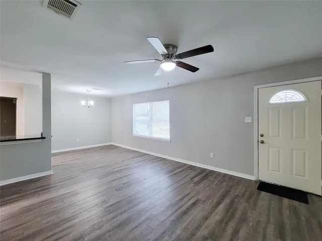 an empty room with wooden floor a ceiling fan and windows