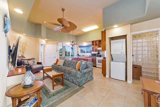 a living room with furniture a refrigerator and kitchen view