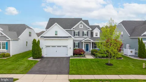 a view of a white house next to a yard with big trees