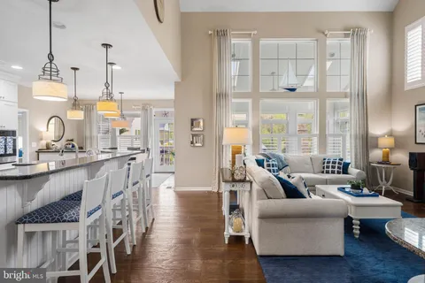 a kitchen with stainless steel appliances granite countertop a refrigerator a oven a sink a stove and a dining table with wooden floor