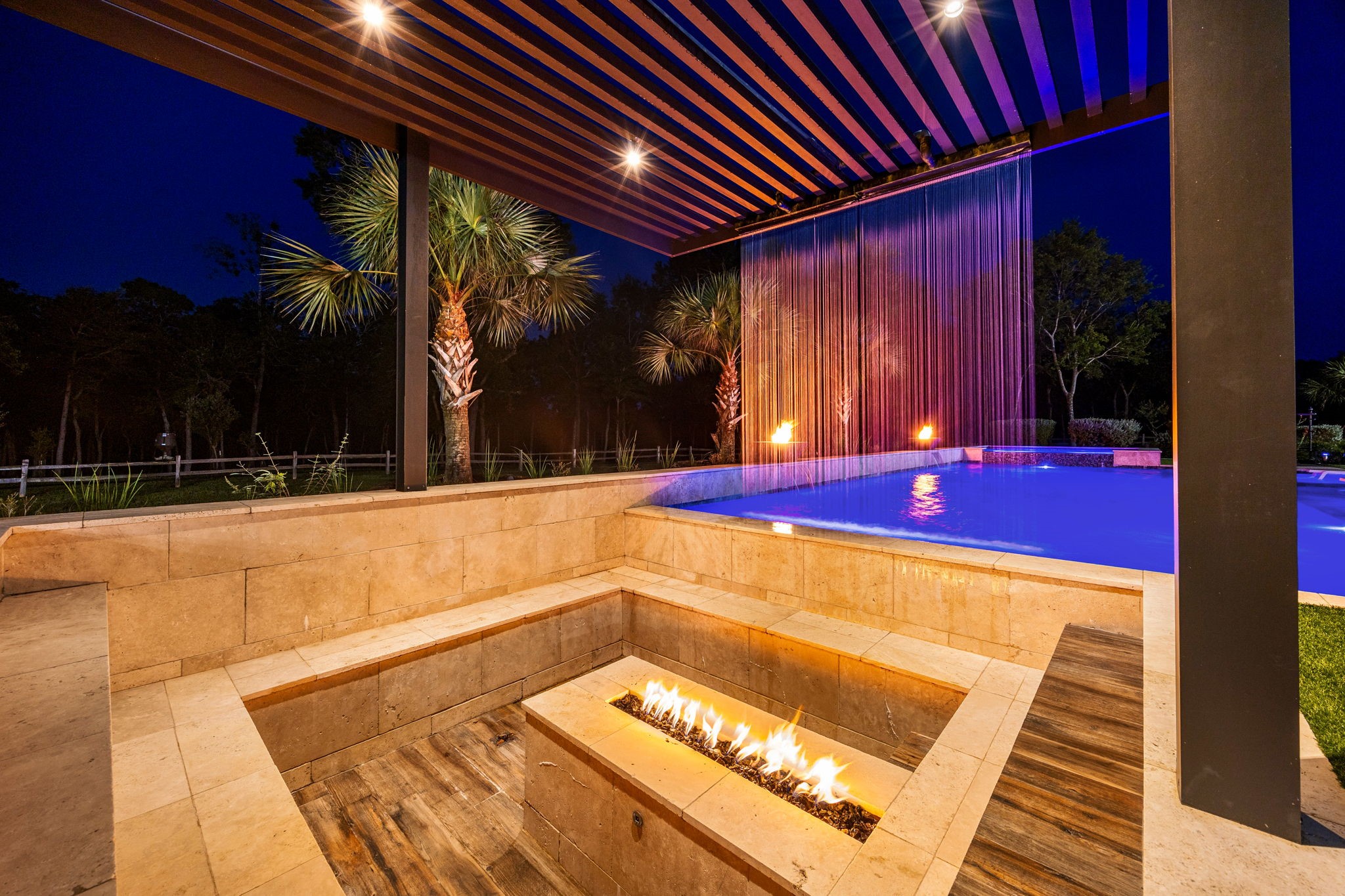 1100 Felder Road Washington, TX 77880 - Photo 40 of 50 A sunken conversation pit with a linear gas fire feature sits just steps from the pool, framed by a dramatic cascading water wall with color-changing lighting — an intimate gathering spot for evening entertaining.