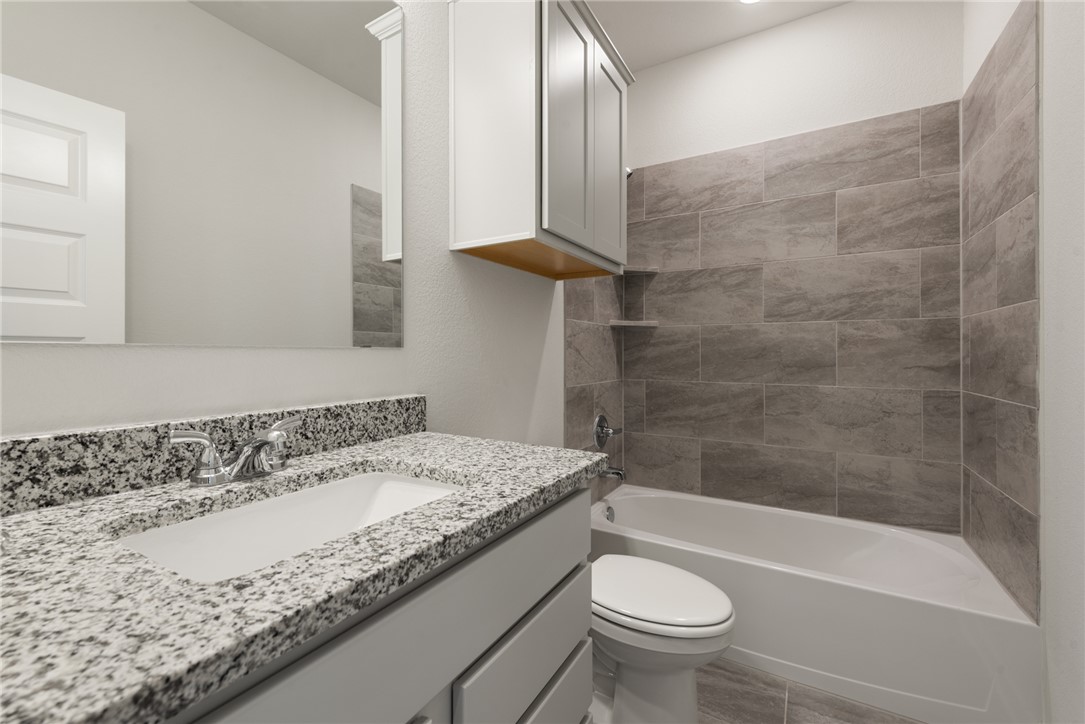 2220 Amber Court Bryan, TX 77807 - Photo 30 of 35 a bathroom with a granite countertop sink a toilet and bathtub
