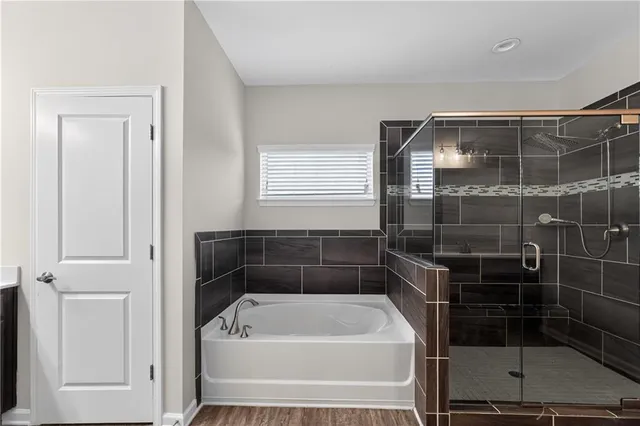 a bathroom with a tub a window and a glass door shower