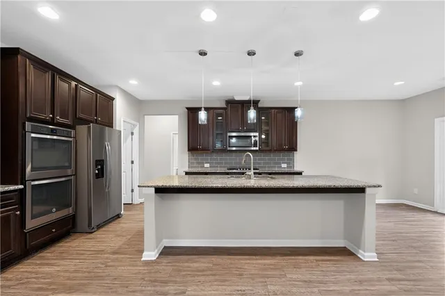 a kitchen with stainless steel appliances granite countertop a sink refrigerator and cabinets