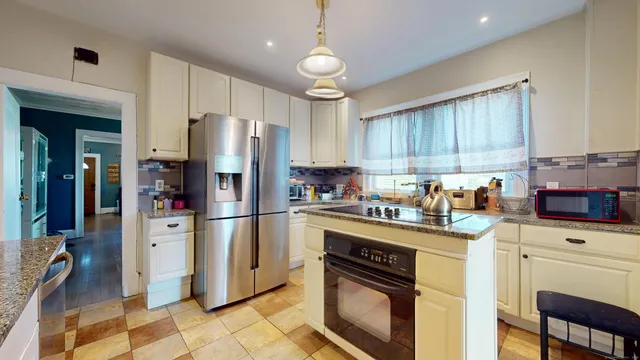a kitchen with granite countertop a refrigerator stove top oven and sink