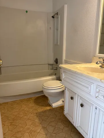 a bathroom with a granite countertop toilet a sink and bathtub