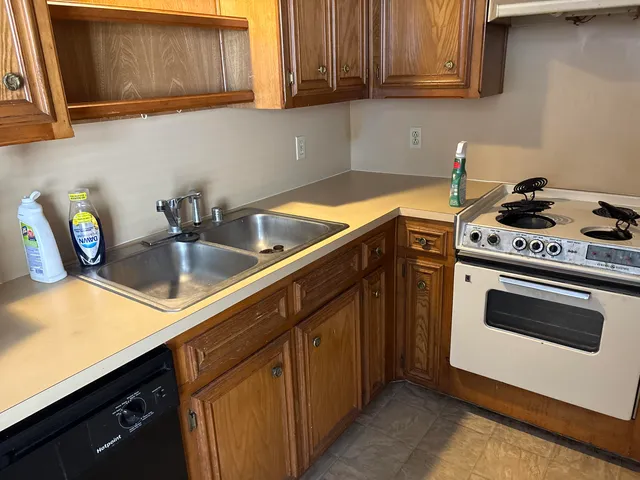 a kitchen with granite countertop a sink a stove and cabinets