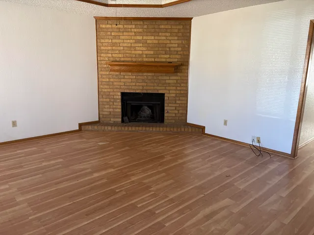 a view of empty room with wooden floor and fireplace