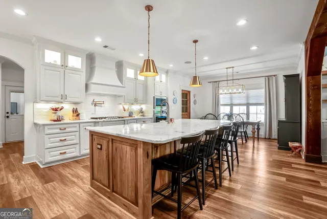 a kitchen with stainless steel appliances kitchen island granite countertop a table chairs and a refrigerator