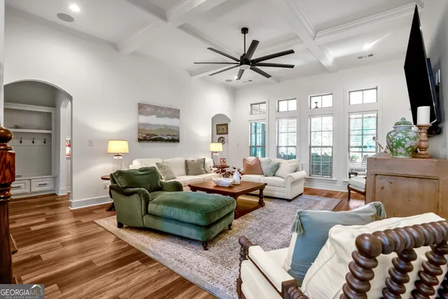 a living room with furniture a ceiling fan a fireplace and a large window