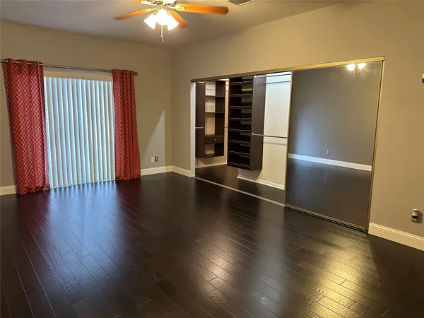 an empty room with wooden floor closet and windows