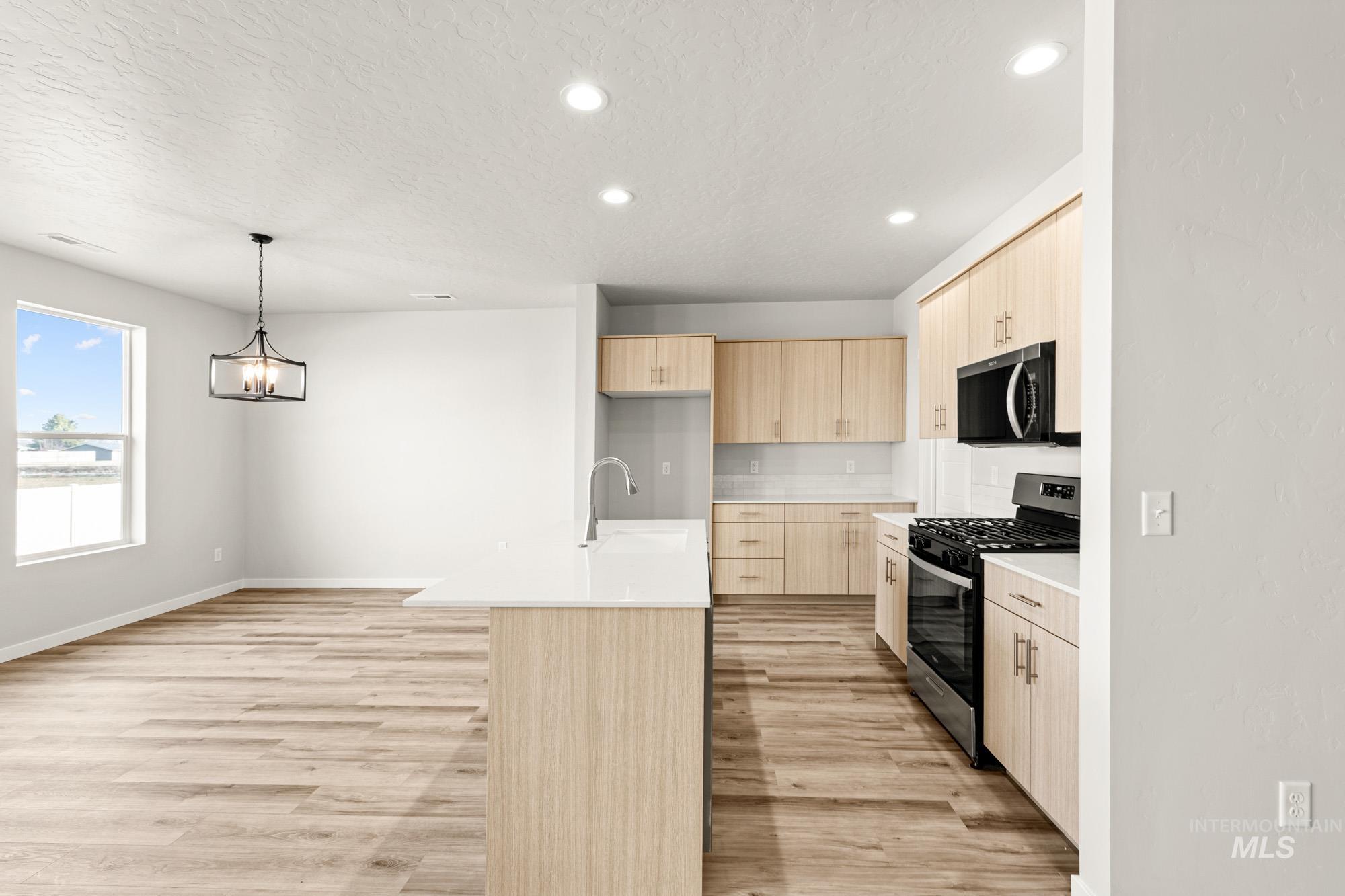 12865 Decatur Street Nampa, ID 83651 - Photo 9 of 20 Open-concept kitchen and dining area featuring wood-finish flooring, recessed lighting, and a modern chandelier