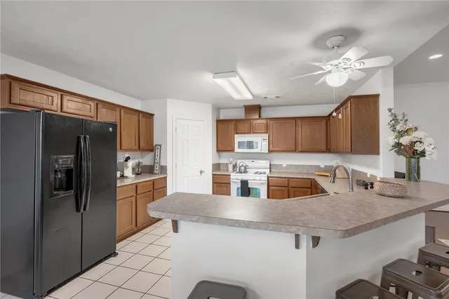 a kitchen with stainless steel appliances granite countertop a sink a refrigerator and a stove top oven