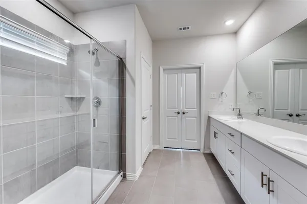 a spacious bathroom with a double vanity sink a mirror and a bathtub