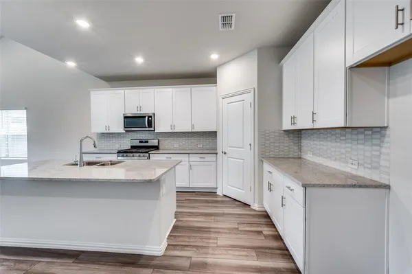 a kitchen with stainless steel appliances granite countertop a stove a sink and a refrigerator