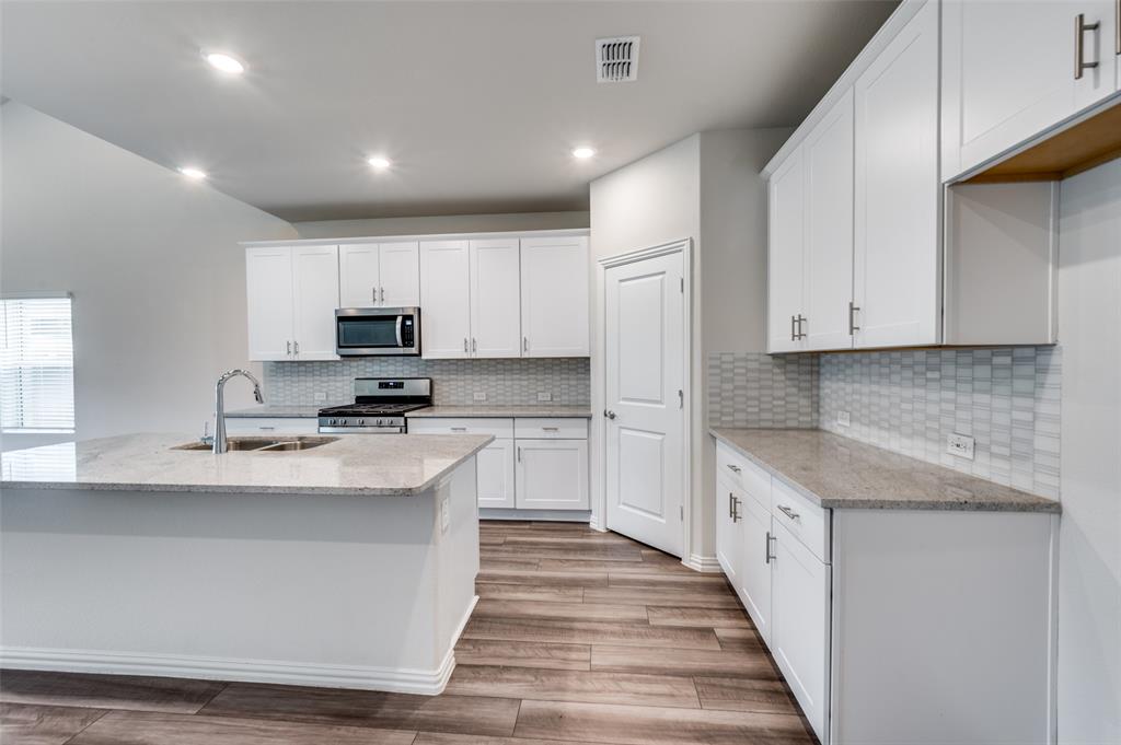 3308 Kingsdown Drive Denton, TX 76207 - Photo 9 of 25 a kitchen with stainless steel appliances granite countertop a stove a sink and a refrigerator