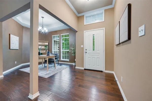 a dining room with wooden floor a chandelier a glass table and chairs