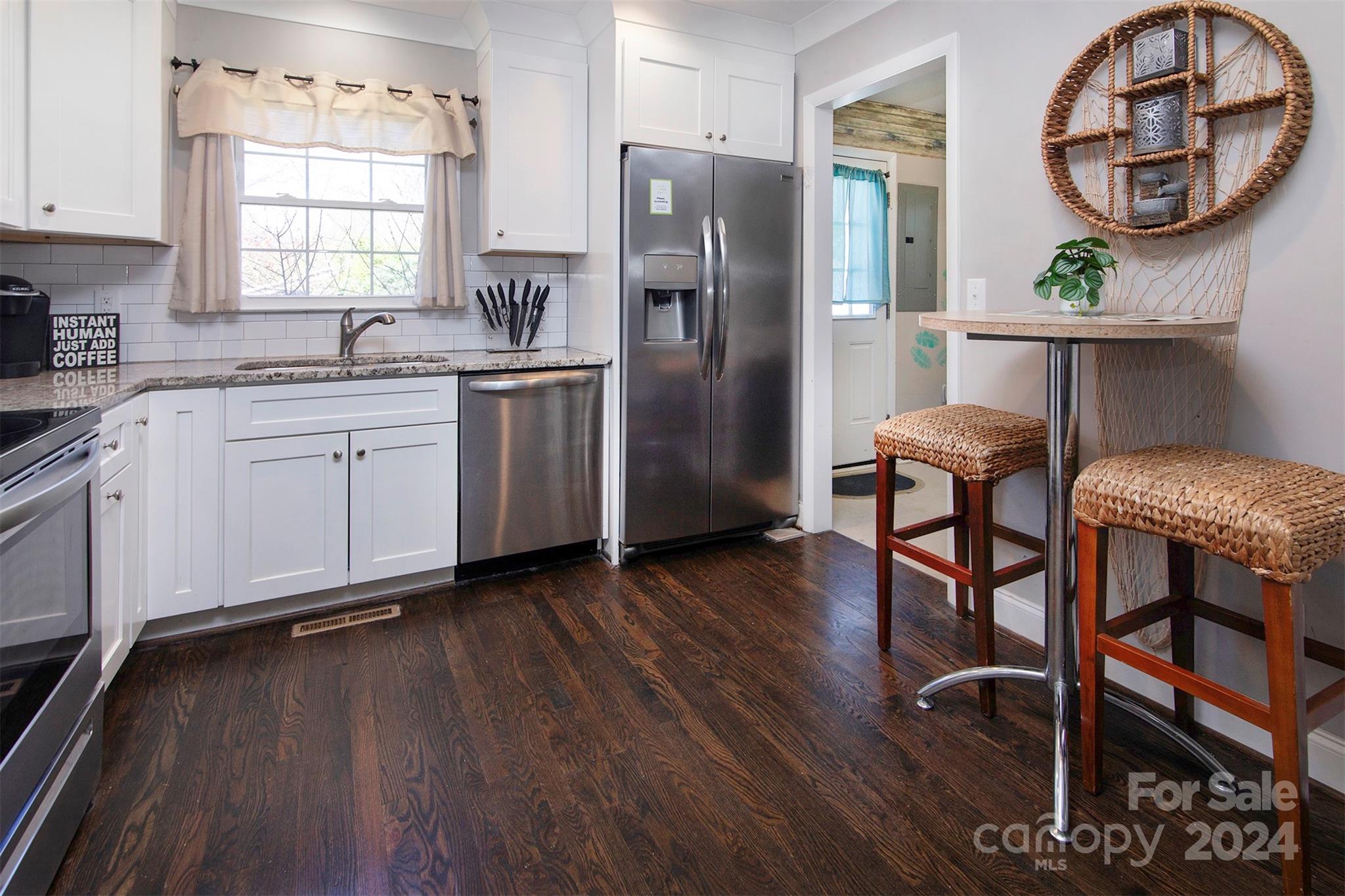 3741 Woodleaf Road Charlotte, NC 28205 - Photo 3 of 31 a kitchen with stainless steel appliances granite countertop a stove a refrigerator a sink dishwasher a dining table and chairs with wooden floor