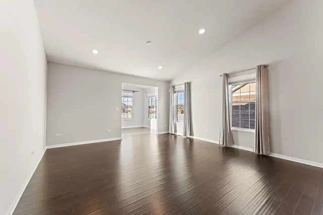 a view of an empty room with wooden floor and windows