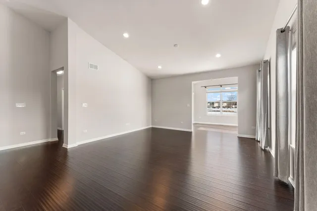 an empty room with wooden floor closet and windows