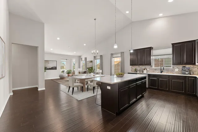 a kitchen with stainless steel appliances kitchen island granite countertop a stove top oven a sink a dining table and chairs