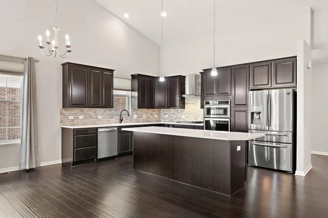 a large kitchen with stainless steel appliances wooden floor and a refrigerator