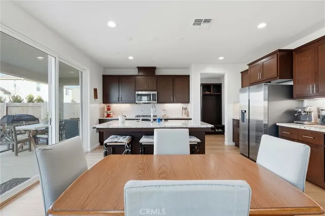 a kitchen with granite countertop a table chairs a sink dishwasher refrigerator and cabinets