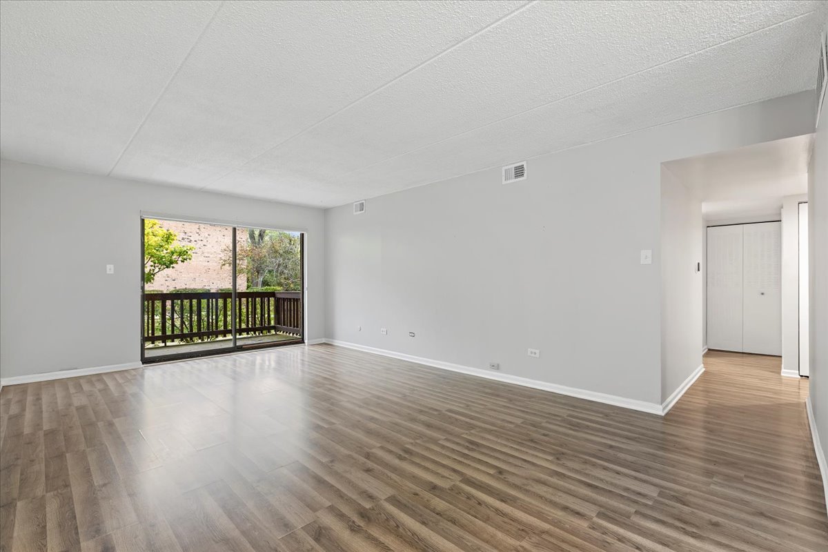 8000 Woodglen Lane, Unit 109 Downers Grove, IL 60516 - Photo 3 of 18 a view of an empty room with wooden floor and a window
