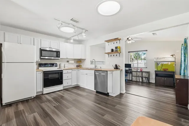 a kitchen with granite countertop a stove a sink dishwasher a refrigerator and a dining table with wooden floor