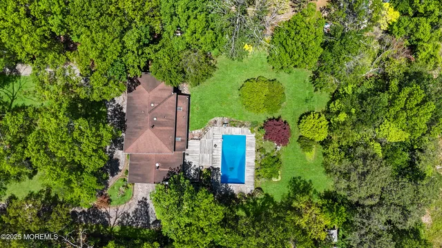 an aerial view of a house with a yard and large trees